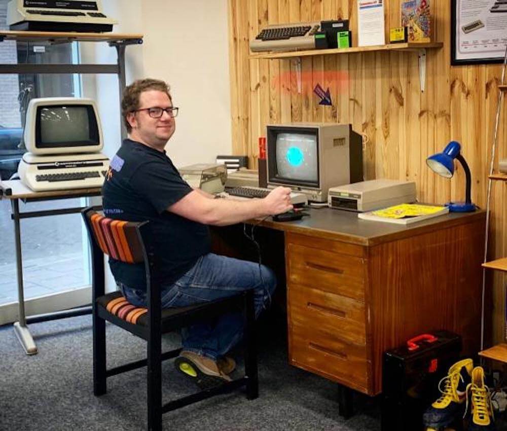 Bart van den Akker achter een bureau met een oude computer in het HomeComputerMuseum