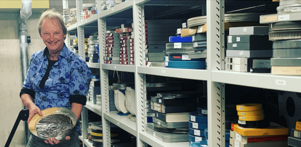 Syds Wiersma in het Fries Film en Audio Archief met een ronde metalen filmdoos in zijn handen