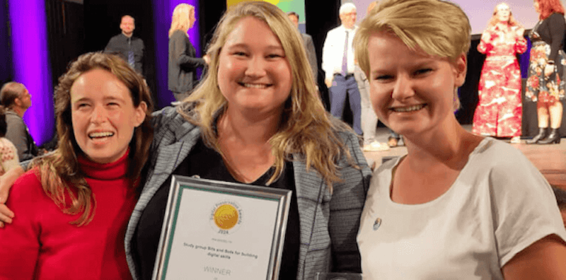 Drie mensen poseren met de Digital Preservation Award in de categorie Teaching and Communications. De persoon in het midden houdt de prijs vast.