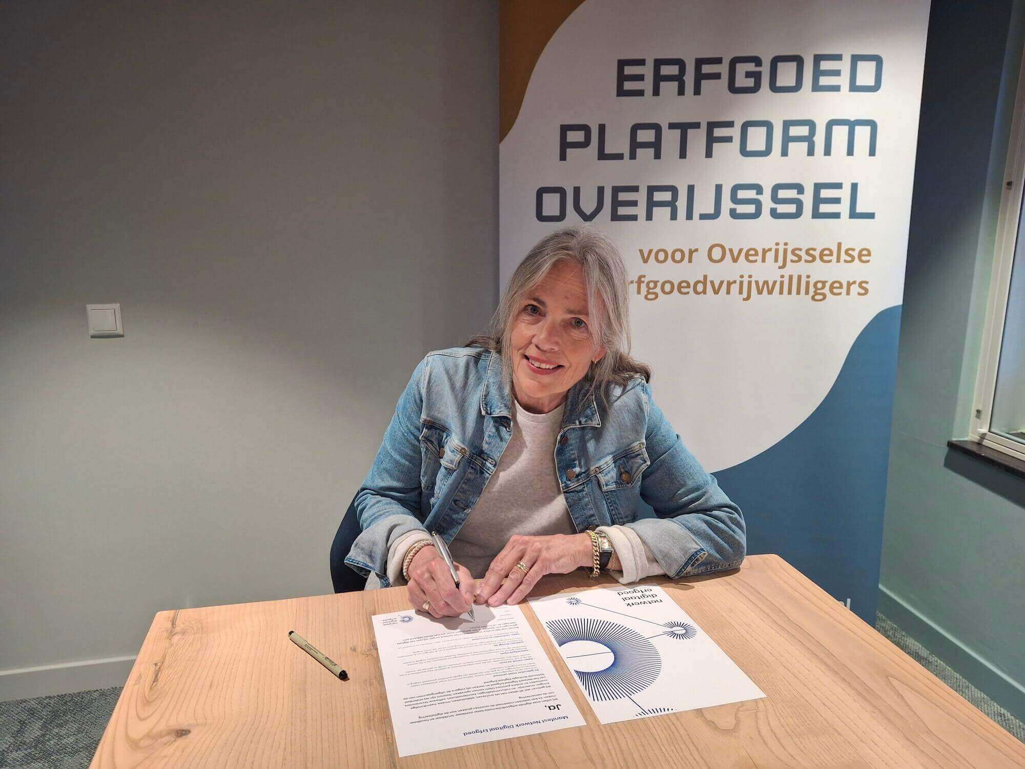 Geeke Snijders-Hoiting, directeur Stichting Overijsselacademie, ondertekent vanachter een bureau het NDE-manifest