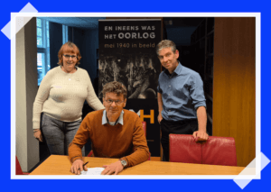 Op de foto v.l.n.r.: Ben Schoenmaker, directeur, zit achter een tafel met het ondertekende manifest. Links van hem staat Nicolette Faber-Wittenberg, hoofd afdeling Publieksinformatie en Collecties, en rechts van hem staat Wouter Brunner, datamanager en senior Adviseur Publieksinformatie en Collecties