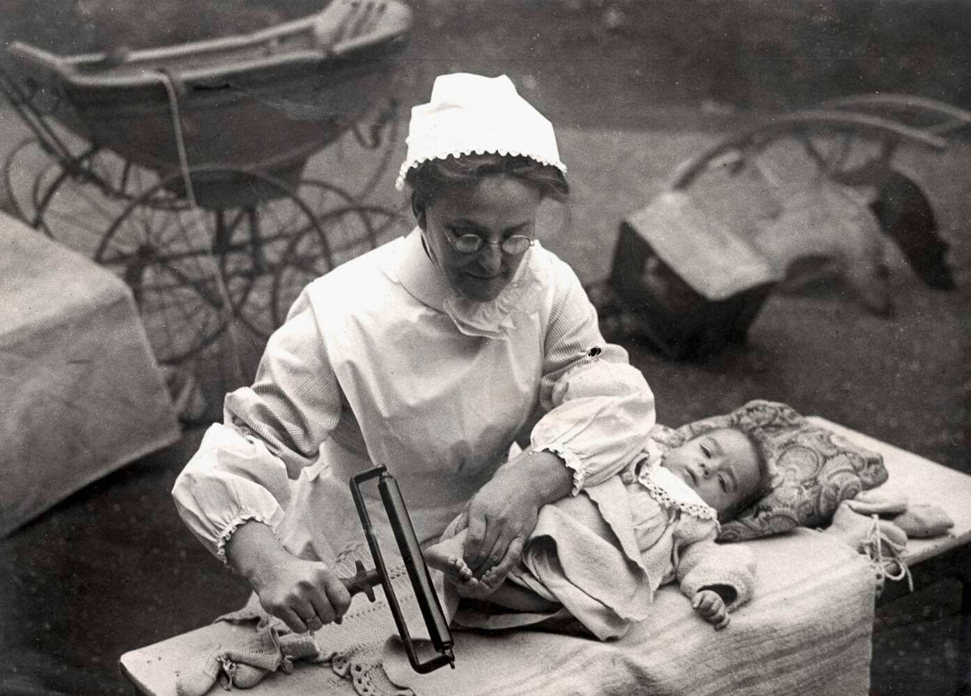 Zwart-witfoto uit 1915 van een verpleegster die een voetafdruk neemt van een pasgeboren baby in een ziekenhuis in Chicago.