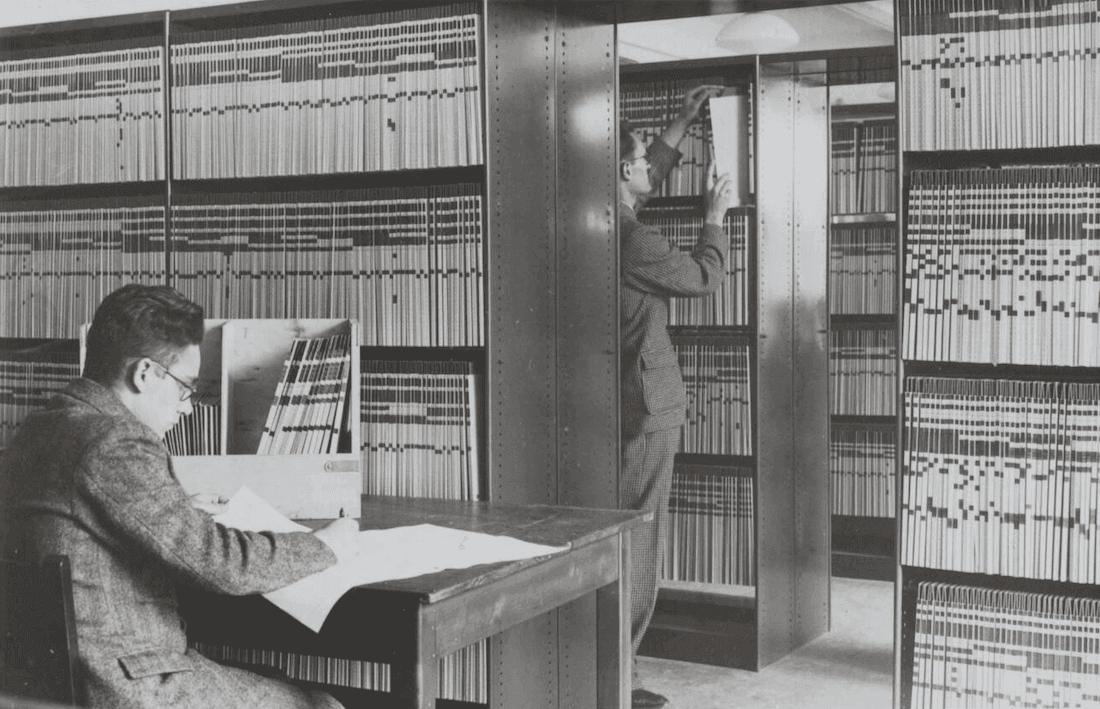 Twee mannen werken in 1940 in het archief van de schade-enquêtecommissie in het Beursgebouw te Rotterdam