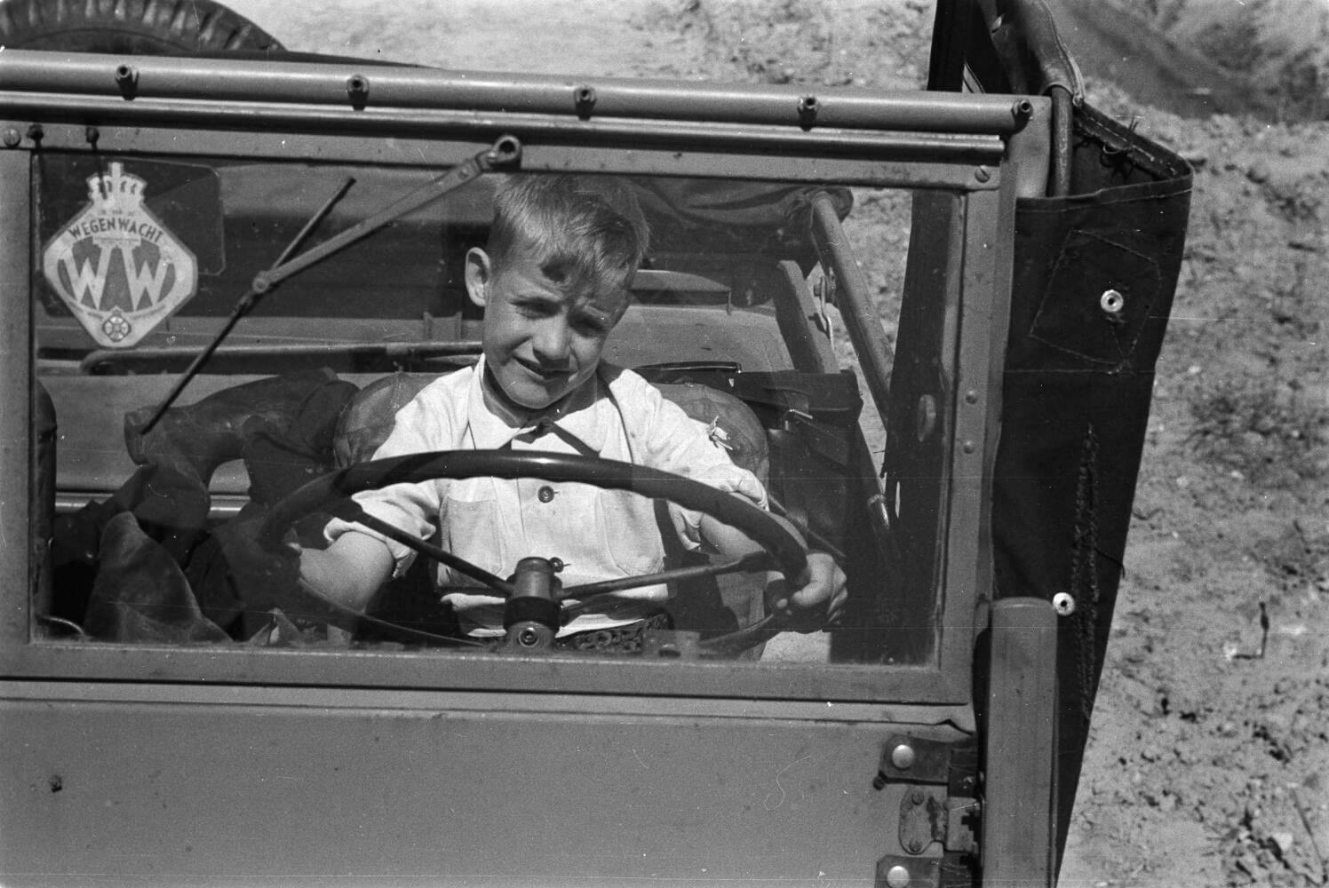 Jongetje achter het stuur van een Wegenwacht-auto, 1948
